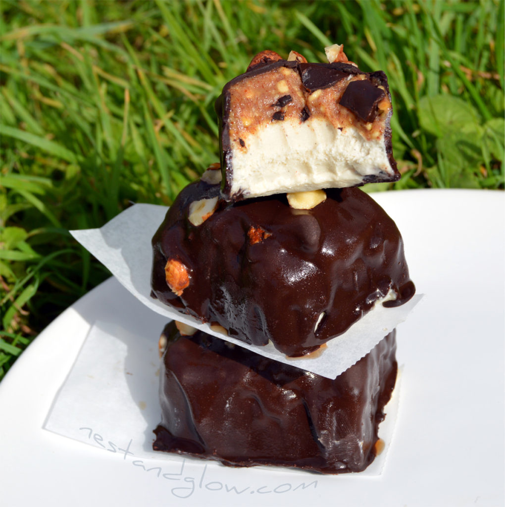 a stacked tower of vegan healthy ice cream snickers. these bites are small but they are fulfilling as they are made with whole food ingredients.