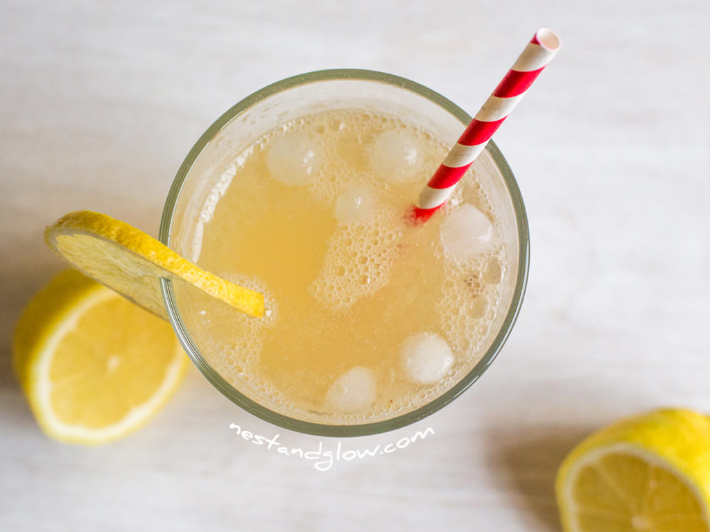 Apple Cider Vinegar Fresh Lemonade in a glass with fresh lemon, ice and raw apple cider vinegar. A paper straw is used here to be plastic free, but usually I would use a reusuable metal straw to save using even compostable paper