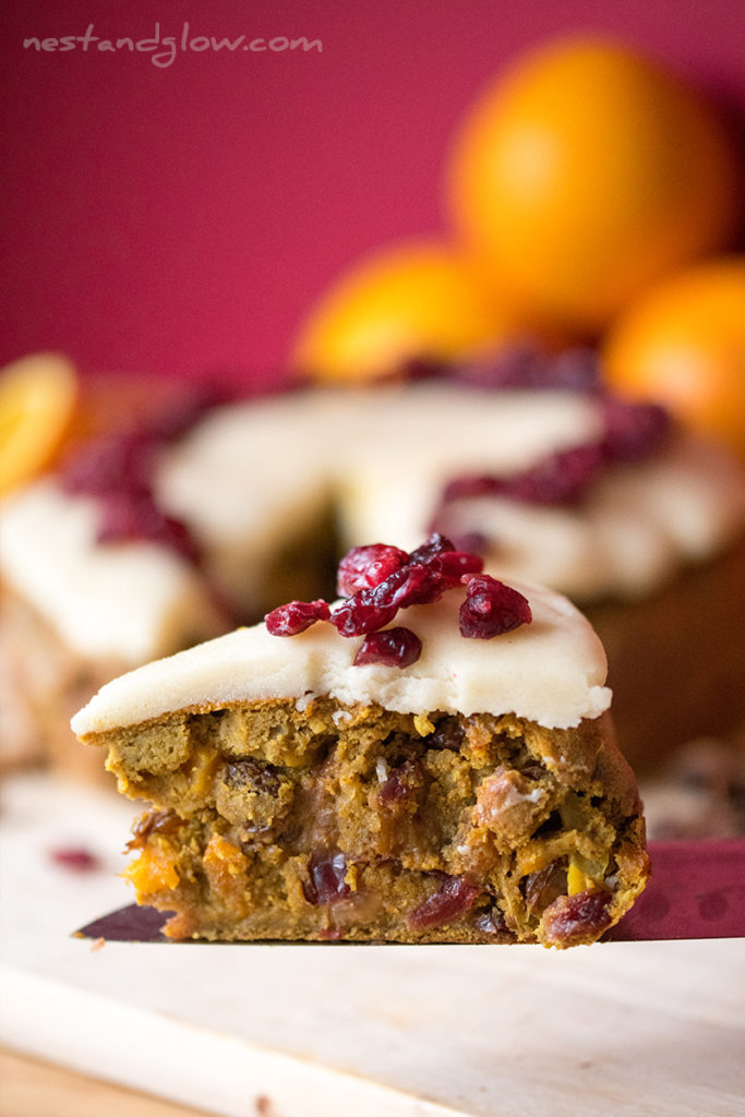 quinoa fruit cake slice on a knife and topped with marzipan and cranberries.