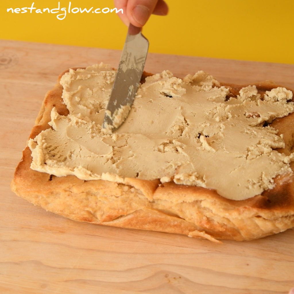 spreading cashew nut paste on top of a healthy cake to make a healthy frosting. no oil or sugar in this creamy dairy free topping